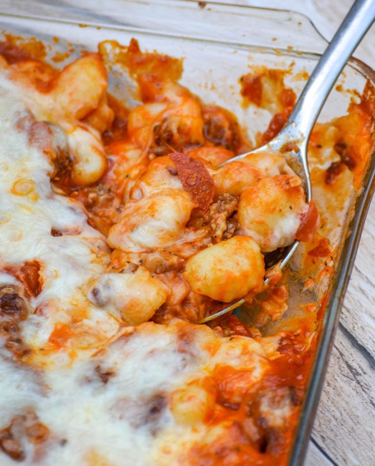 a silver spoon scooping pepperoni pizza gnocchi bake out of a glass casserole dish