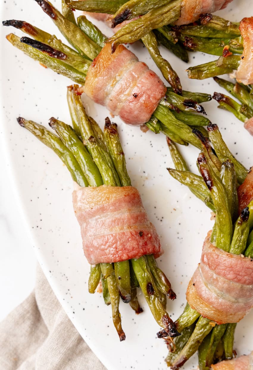 bacon wrapped green bean bundles on a white serving platter