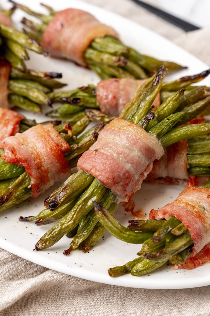 bacon wrapped green bean bundles on a white serving platter