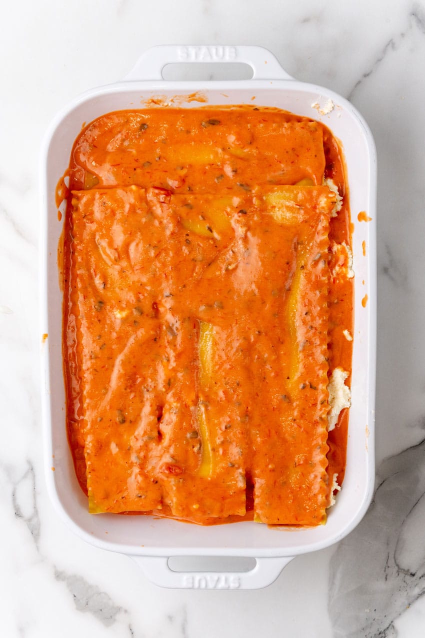 a layer of lasagna with blush sauce arranged in a white baking dish