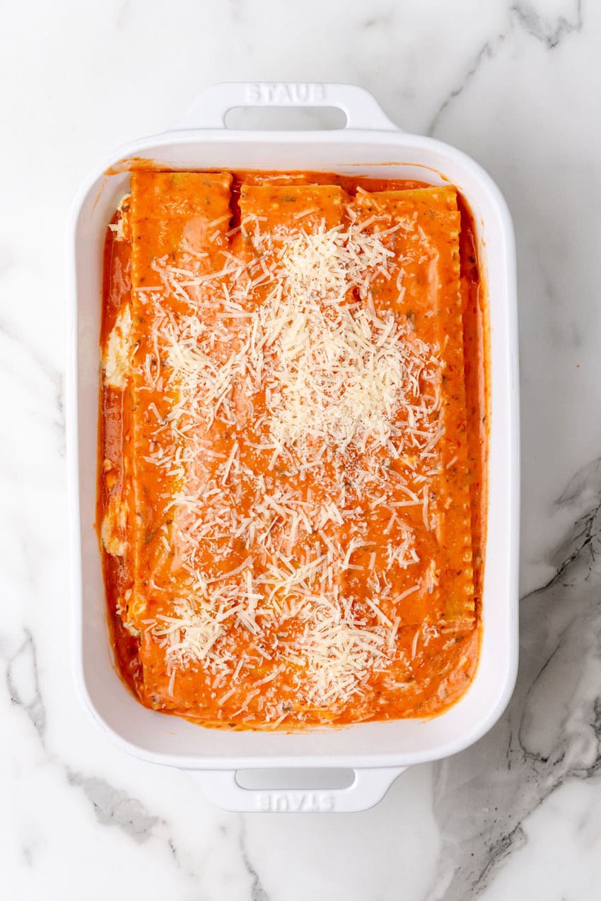 a layer of lasagna with blush sauce arranged in a white baking dish