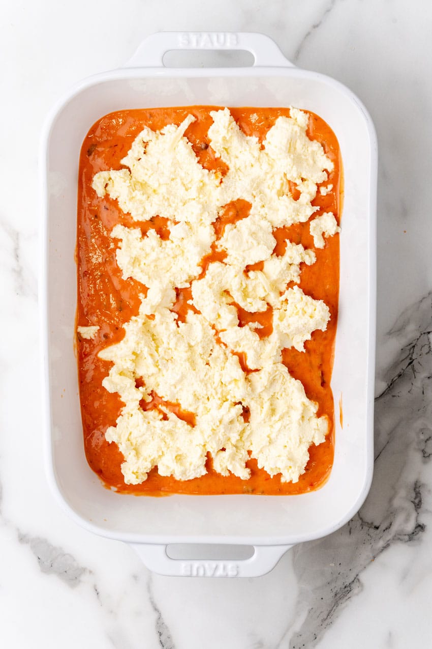 a layer of lasagna with blush sauce arranged in a white baking dish