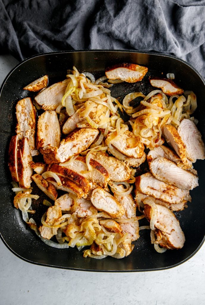 sliced seasoned cooked chicken breasts & caramelized onions together in a large black skillet