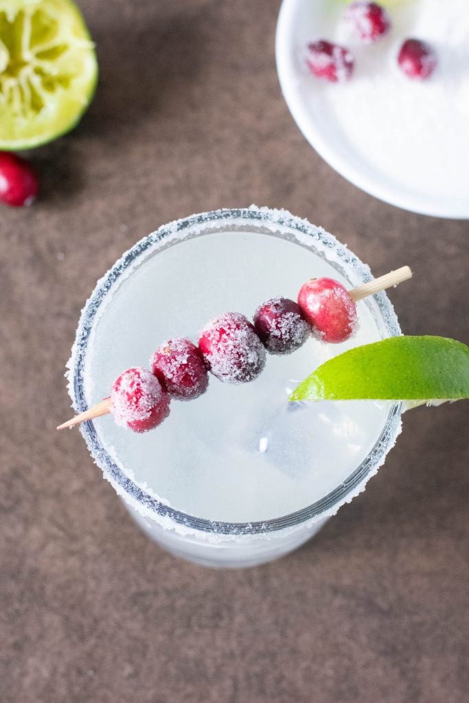 overhead view of glass of margarita with cranberries on top