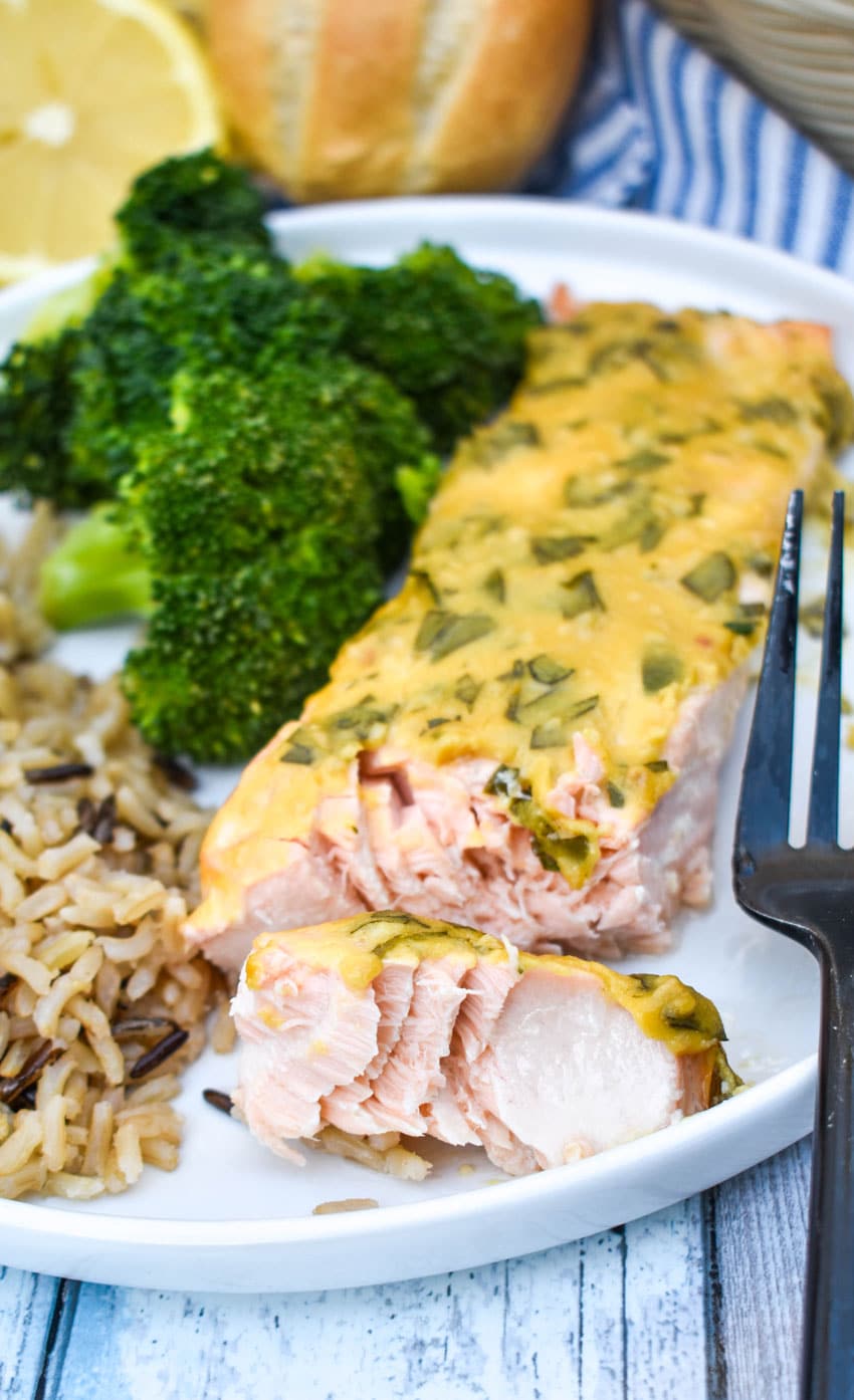 a slice of dijon mustard salmon on a white plate with a black fork on the side