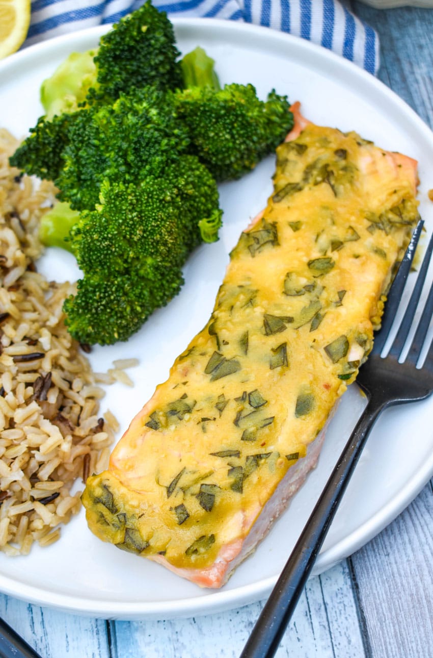 a slice of dijon mustard salmon on a white plate with a black fork on the side