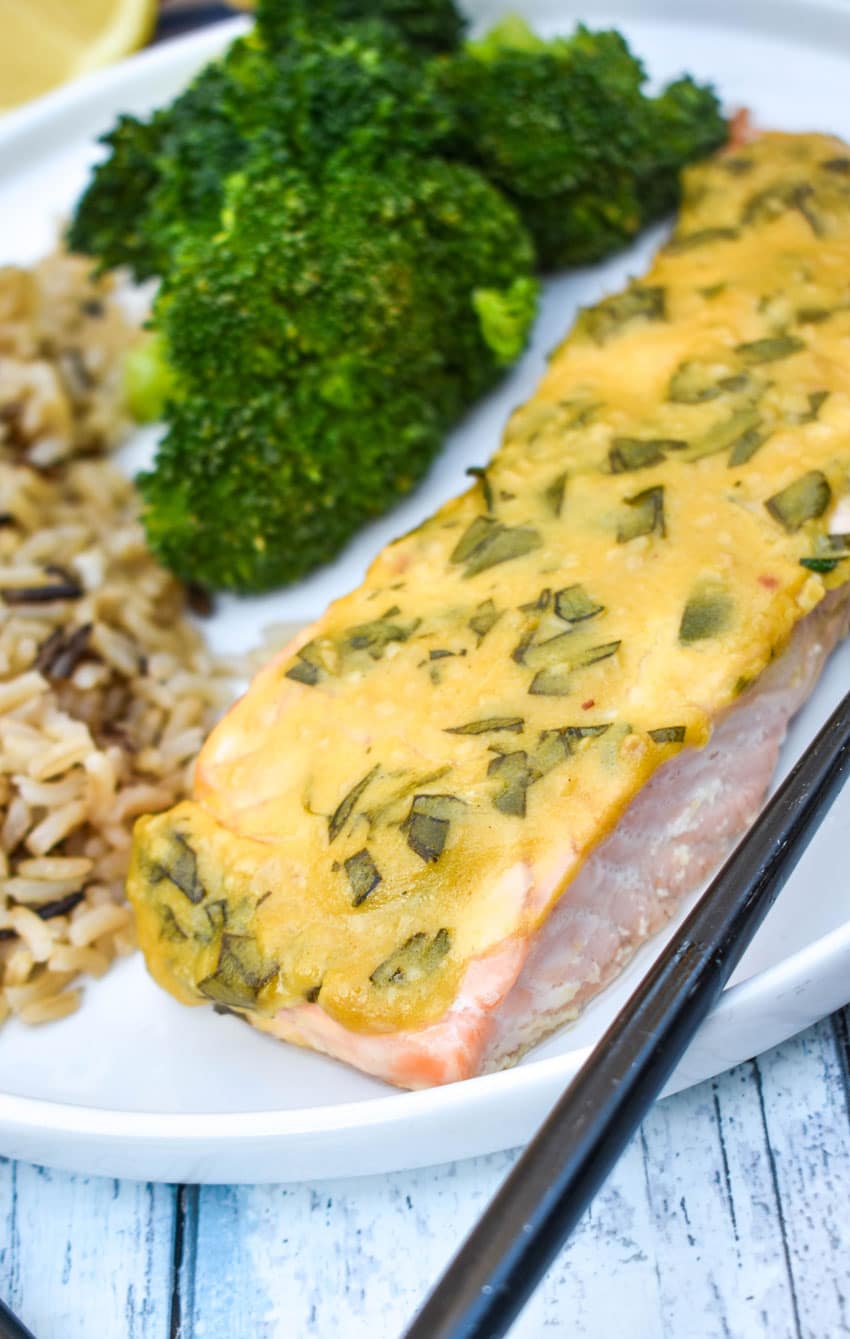 a slice of dijon mustard salmon on a white plate with a black fork on the side