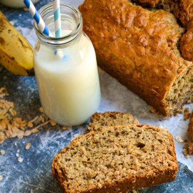 SLICES OF BANANA OAT BREAD ON A BLUE COUNTERTOP WITH RAW OATS SPRINKLED AROUND