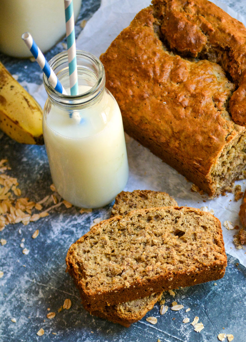 SLICES OF BANANA OAT BREAD ON A BLUE COUNTERTOP WITH RAW OATS SPRINKLED AROUND