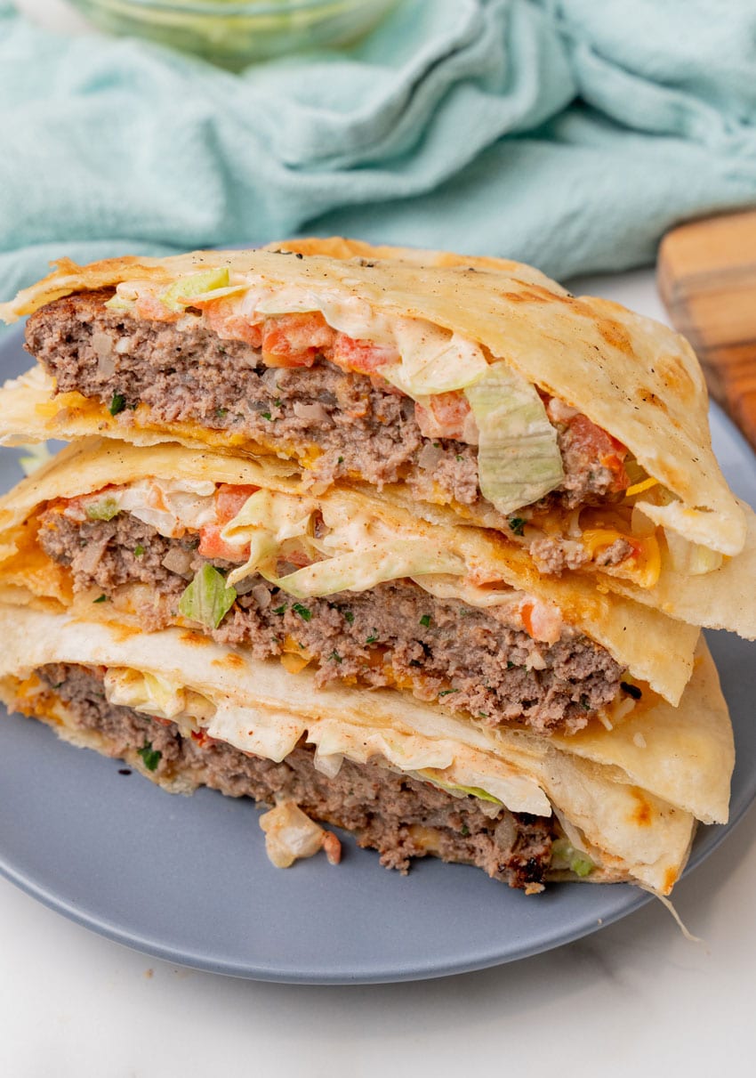 a stack of three quesadilla burger halves on a blue plate
