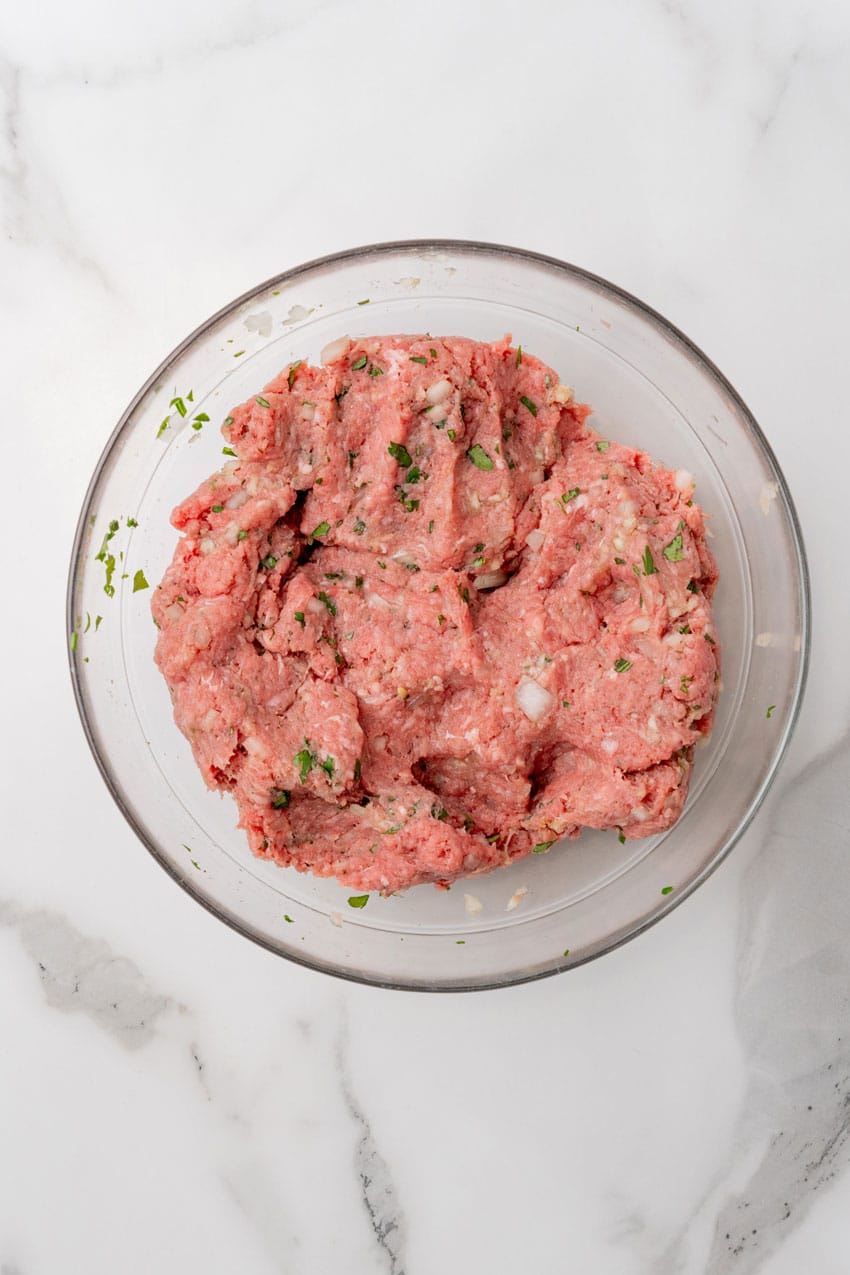 seasoned hamburger meat mixture in a glass mixing bowl