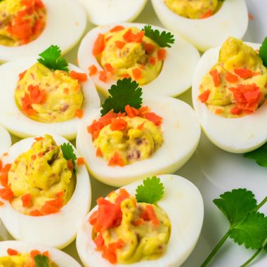 Irish deviled eggs on arranged on a white platter with fresh herbs