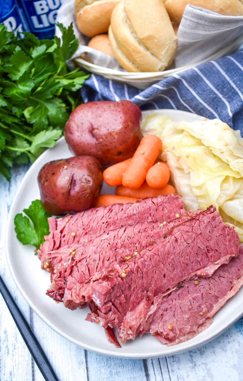 slices of corned beef brisket with red potatoes carrots and cabbage on a white dinner plate