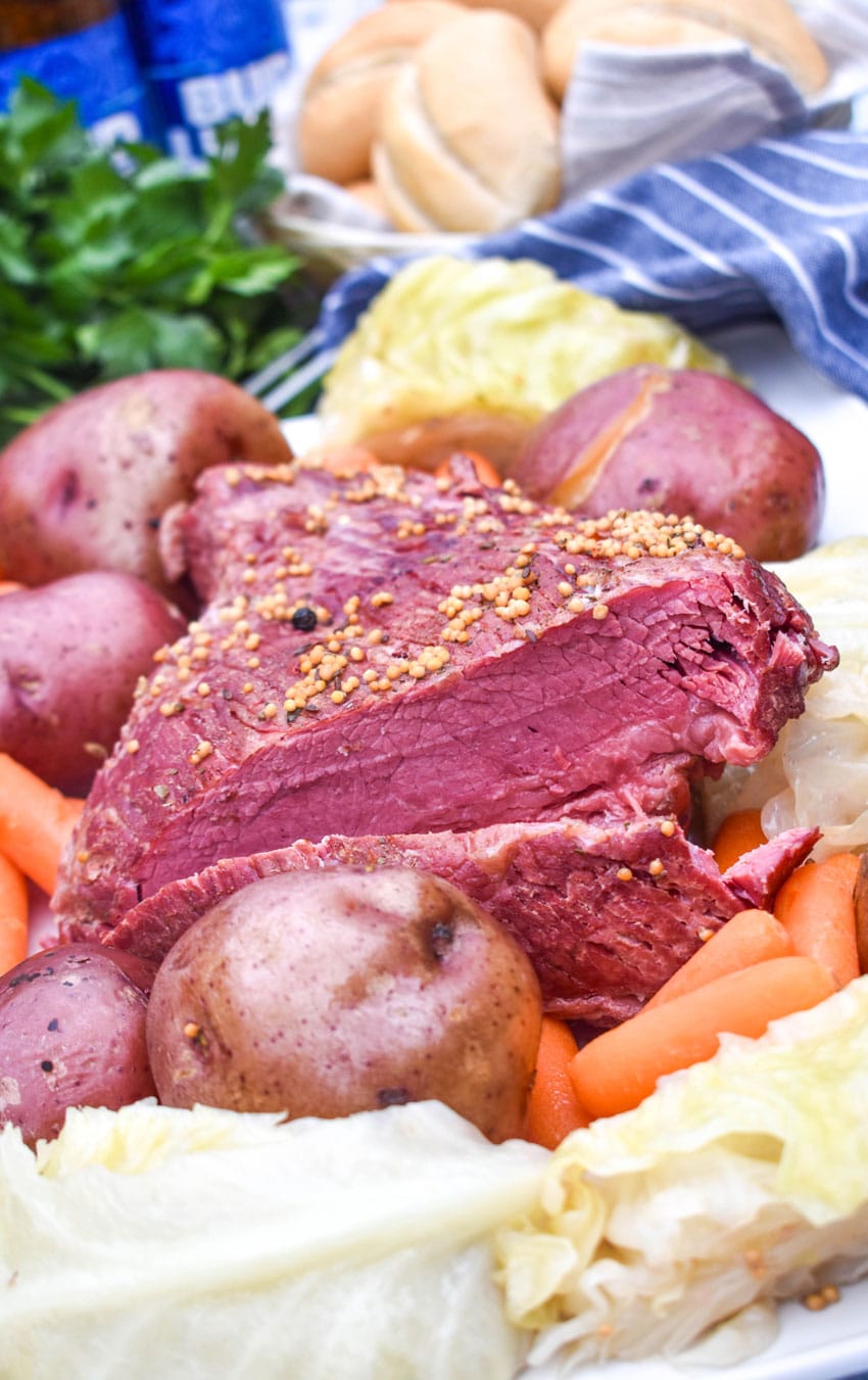 a cooked corned beef brisket surrounded by potatoes carrots and cabbage