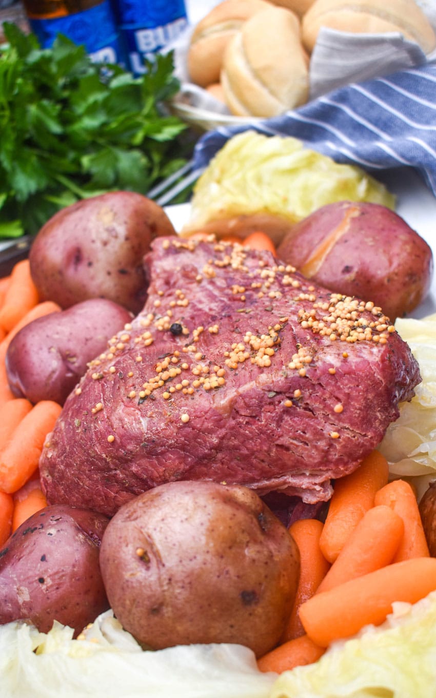 a cooked corned beef brisket surrounded by potatoes carrots and cabbage