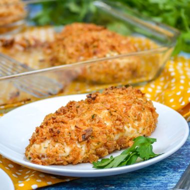 onion crusted herbed chicken on a white plate with fresh parsley leaves