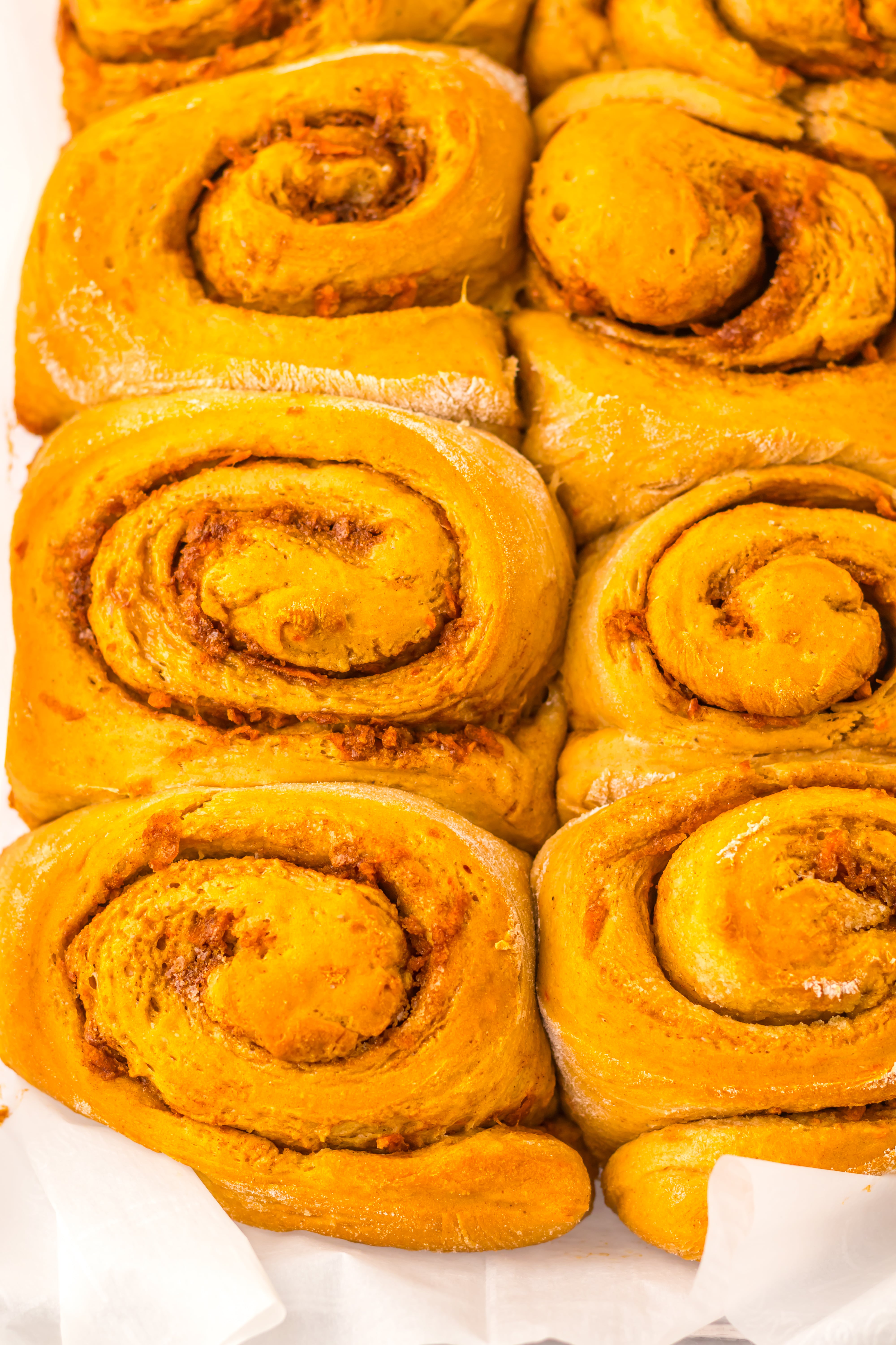unfrosted baked carrot cake cinnamon rolls in a glass baking dish