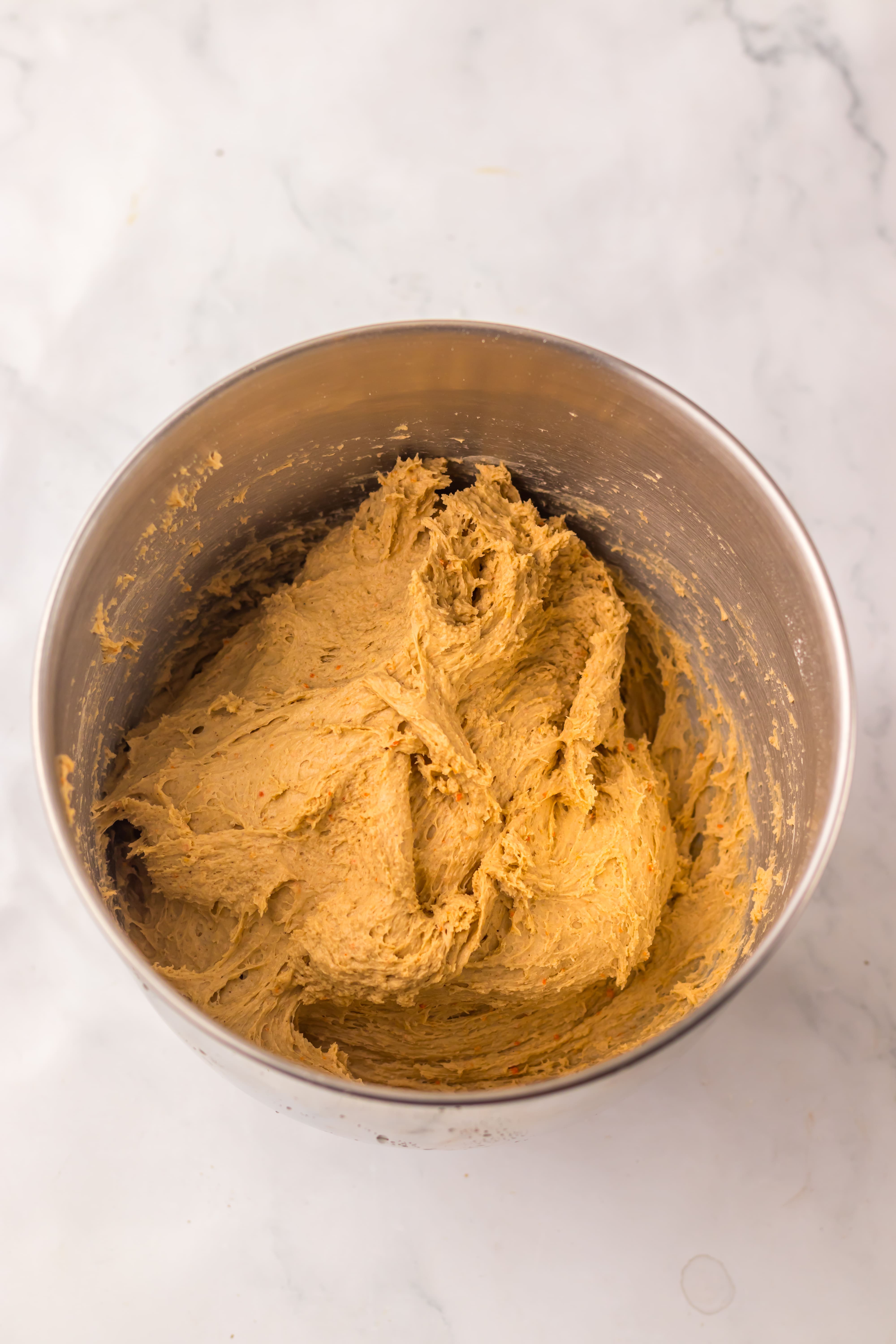 carrot cake cinnamon rolls dough in a metal mixing bowl