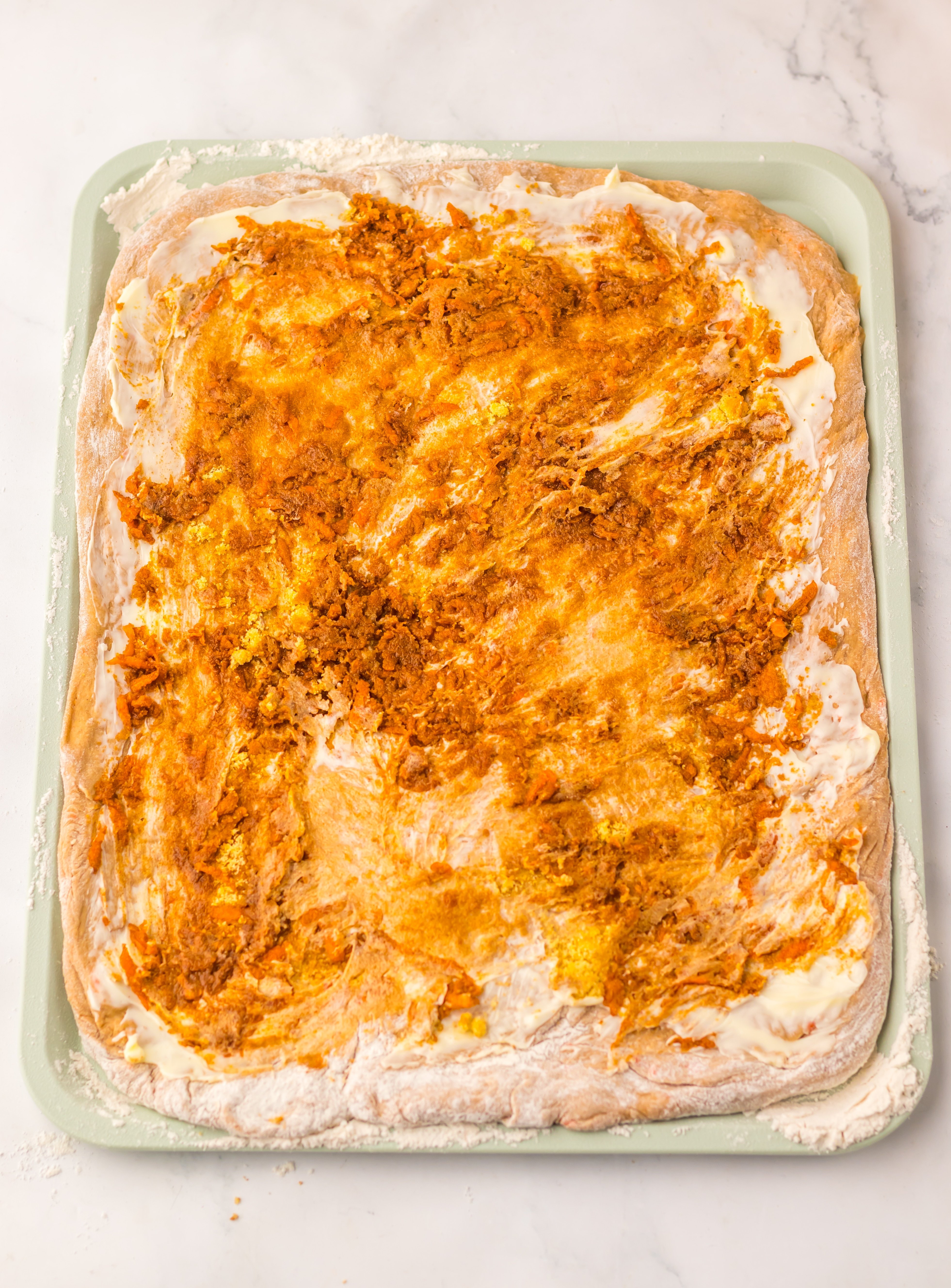 rolled out carrot cake cinnamon roll dough spread with softened butter and brown sugar and orange zest mixture