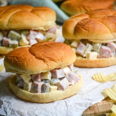 CUBAN HAM SALAD SANDWICHES ON A WRINKLED SHEET OF WHITE PARCHMENT PAPER