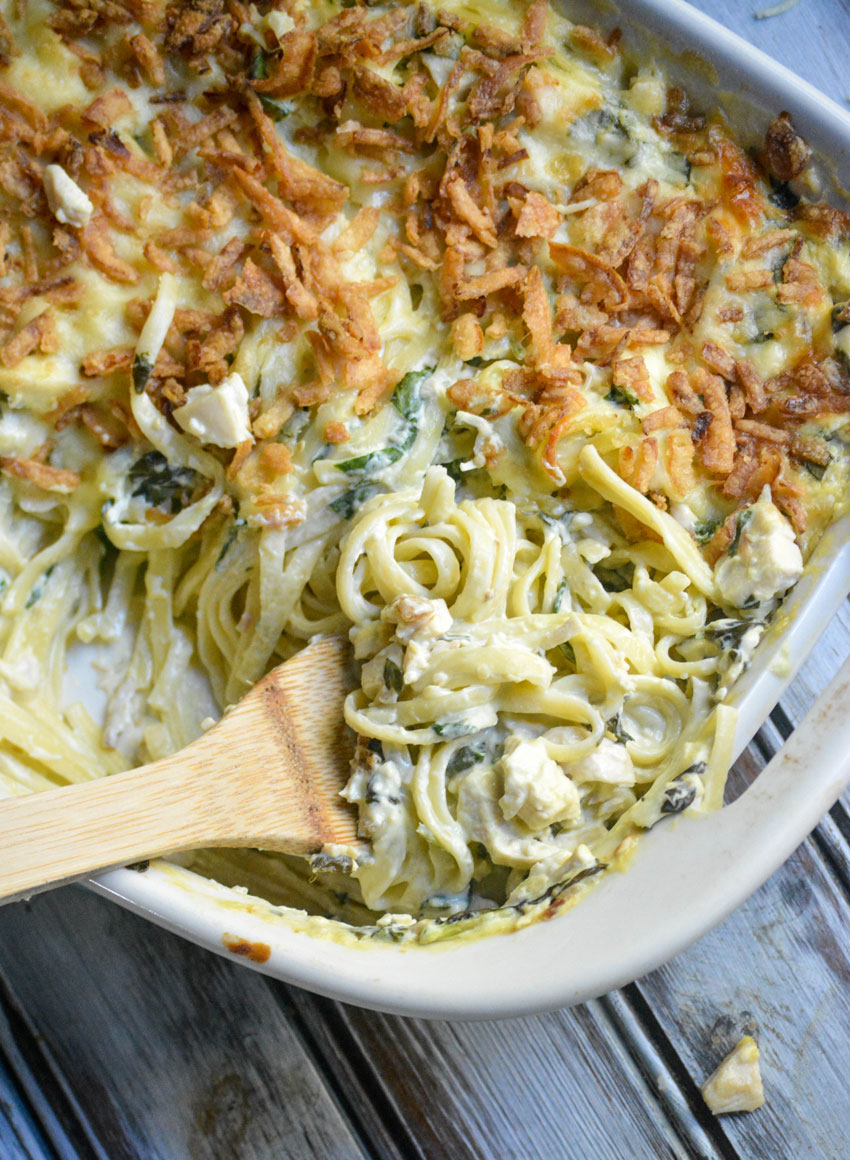 A WOODEN SPOON SCOOPING MONTERREY CHICKEN SPAGHETTI OUT OF A CASSEROLE DISH