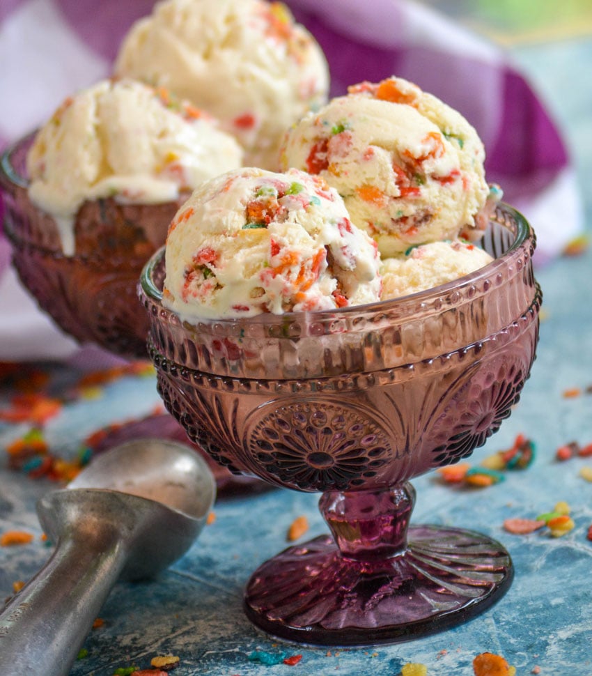 scoops of fruity pebble ice cream in purple glass bowls