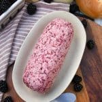 a log of whipped blackberry butter on a small dish on a wooden cutting board