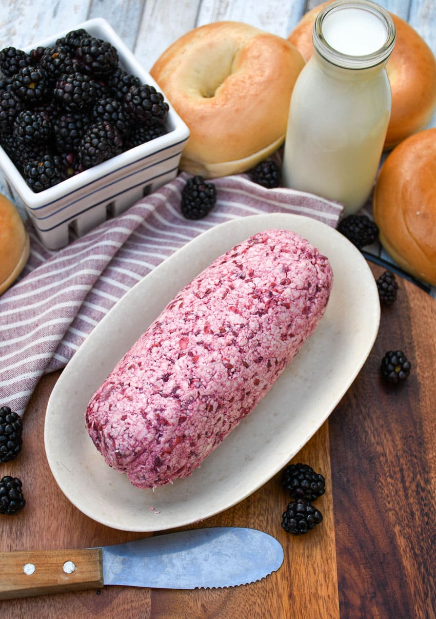 a log of whipped blackberry butter on a small dish on a wooden cutting board