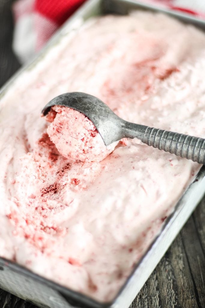 no churn red velvet ice cream being scooped from a metal loaf pan