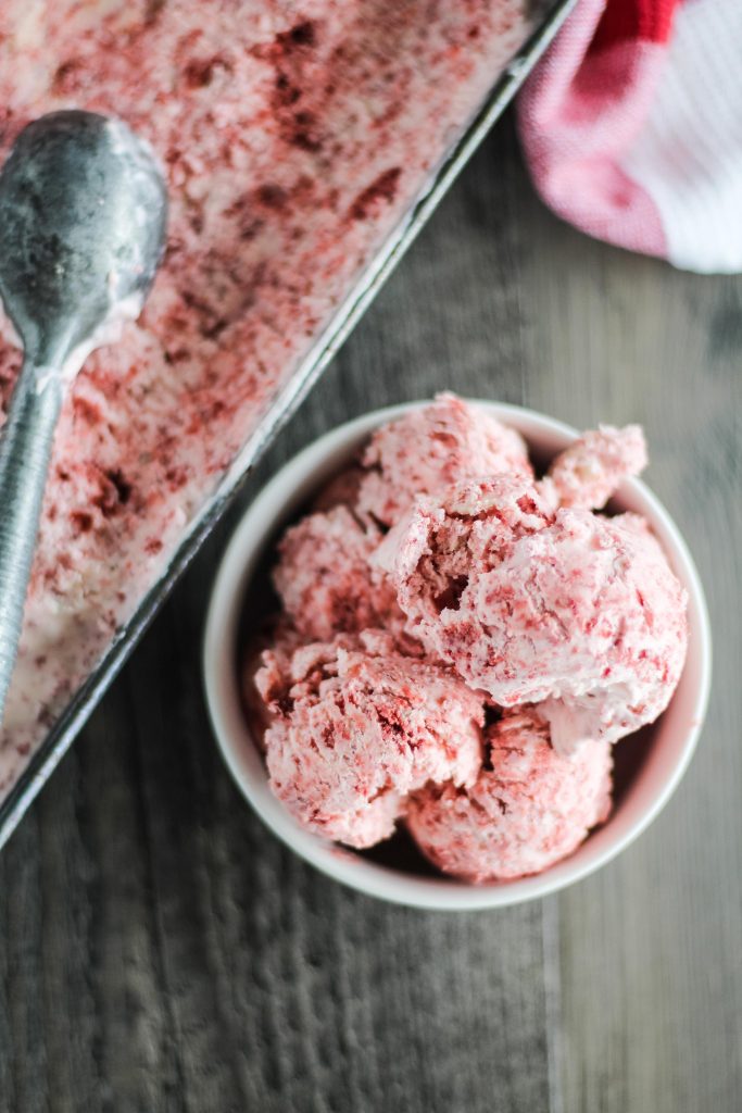 scoops of no churn red velvet ice cream in a white bowl on a brown background