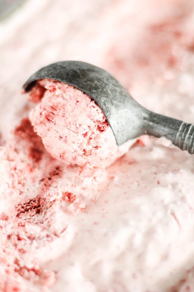 a close up shot of no churn red velvet ice cream being scooped from a metal loaf pan