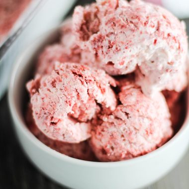 scoops of no churn red velvet ice cream in a white bowl on a brown background