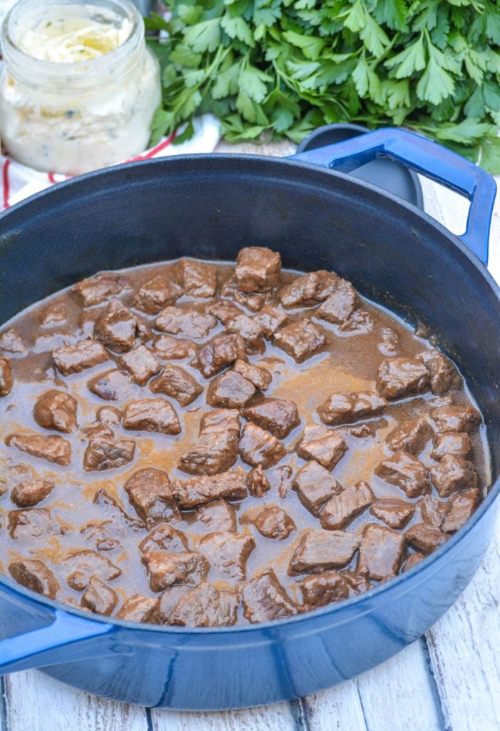 chunks of stew beef in brown gravy in a blue pot