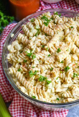creamy macaroni salad in a glass bowl on top of a red checkered cloth napkin