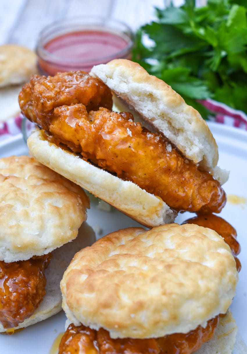 a stack of hot honey chicken biscuit sandwiches on a white plate