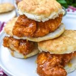 a stack of hot honey chicken biscuit sandwiches on a white plate