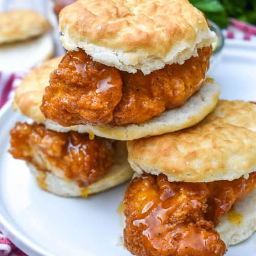 a stack of hot honey chicken biscuit sandwiches on a white plate