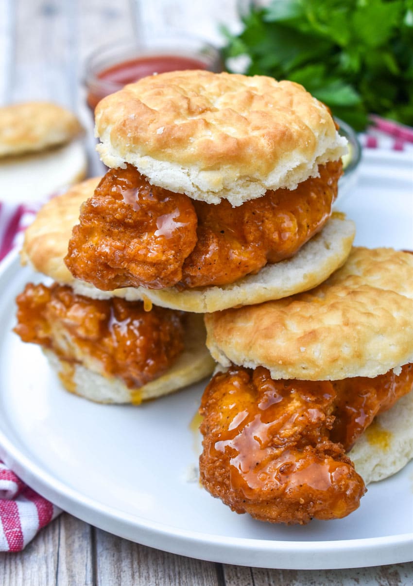 a stack of hot honey chicken biscuit sandwiches on a white plate