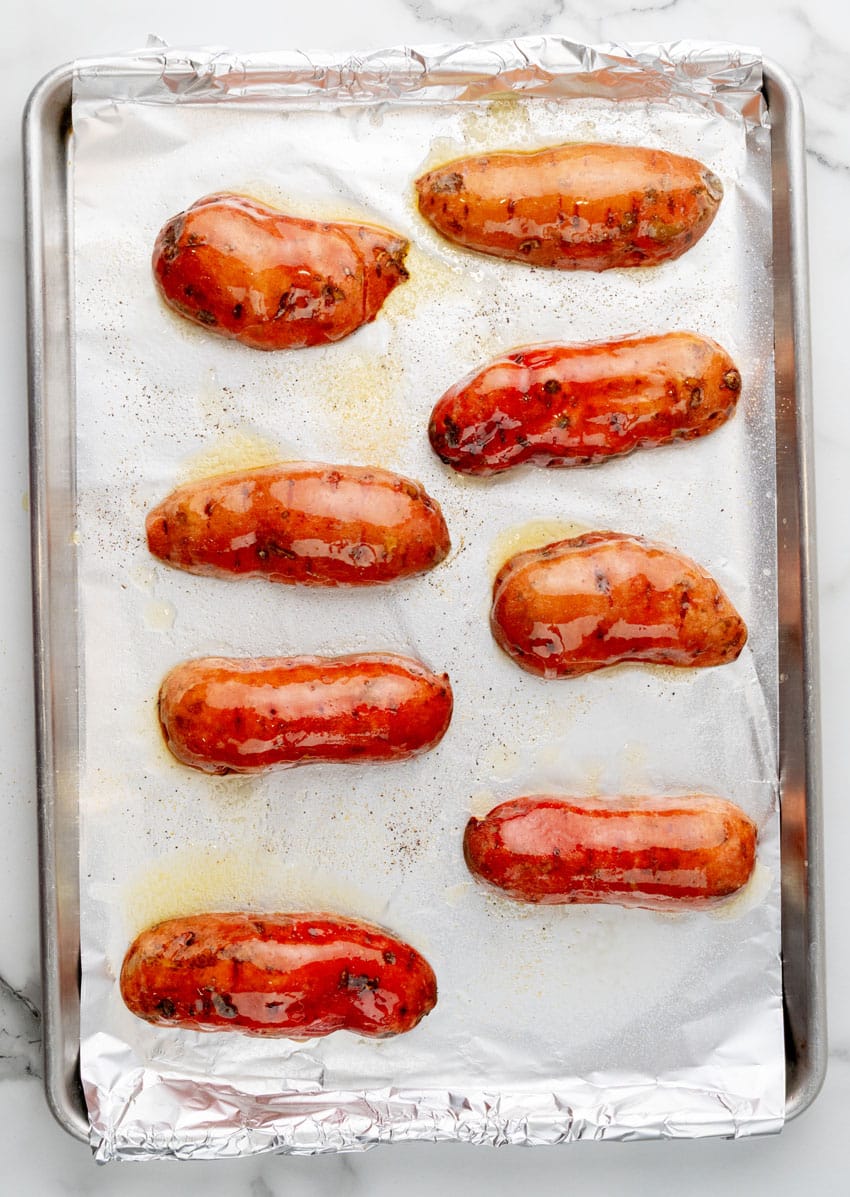 butter brushed sweet potato halved on a foil lined baking sheet