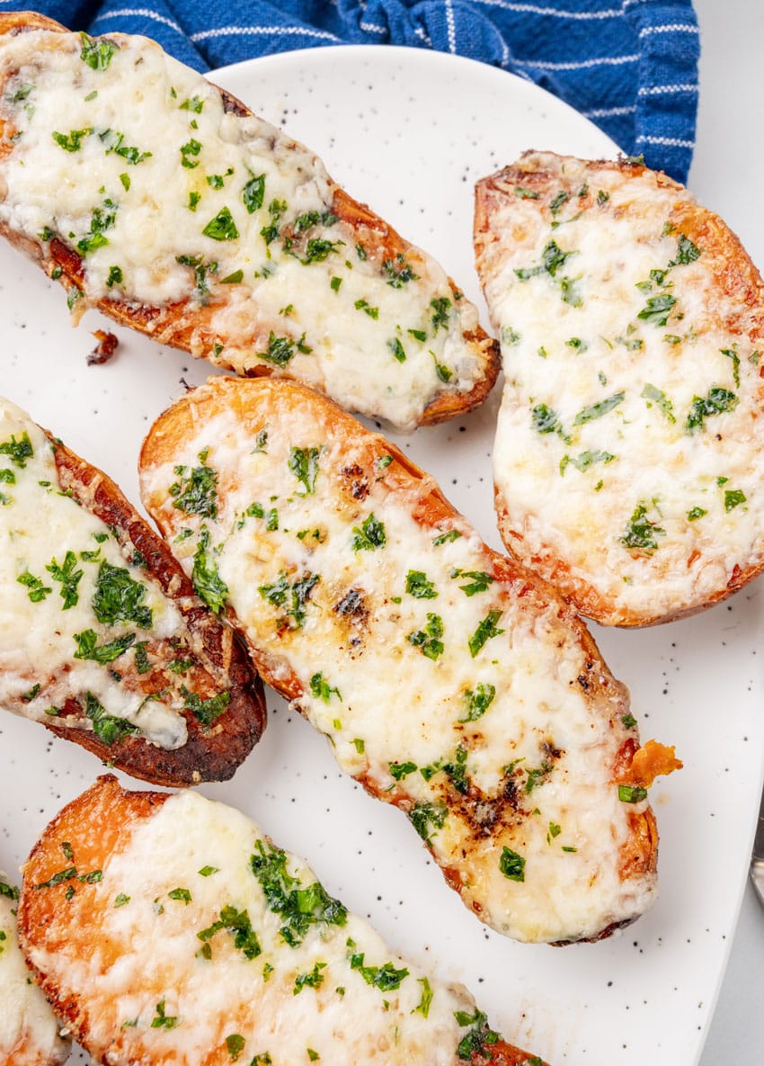 cheesy garlic roasted sweet potatoes on a white serving platter