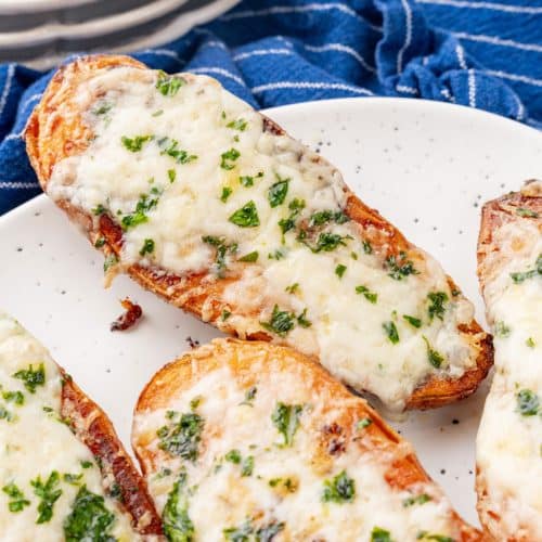 cheesy garlic roasted sweet potatoes on a white serving platter