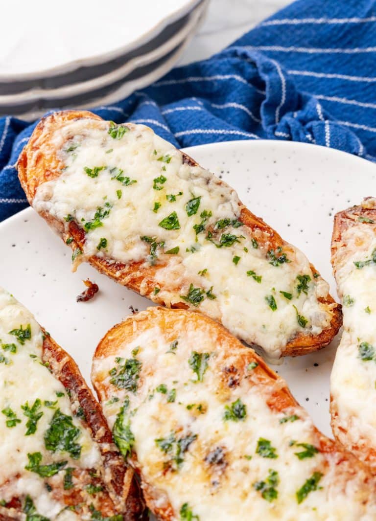 cheesy garlic roasted sweet potatoes on a white serving platter