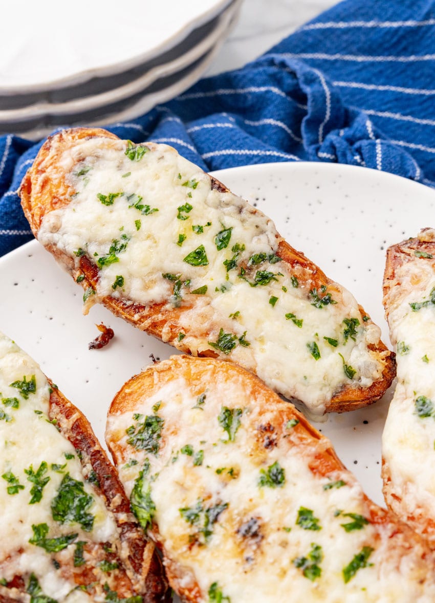 cheesy garlic roasted sweet potatoes on a white serving platter