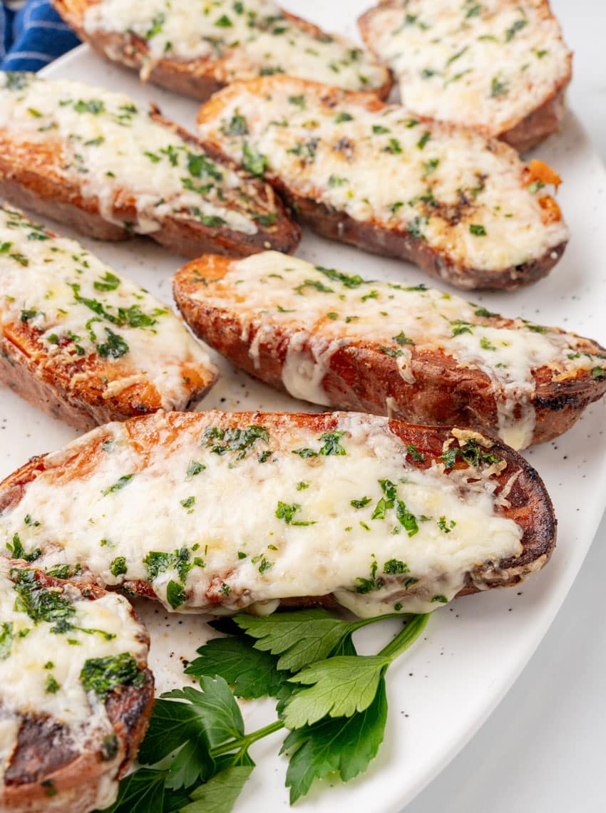 cheesy garlic roasted sweet potatoes on a white serving platter
