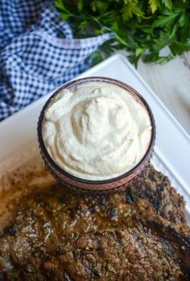 creamy horseradish sauce in a purple glass serving bowl shown with grilled steaks on a white platter