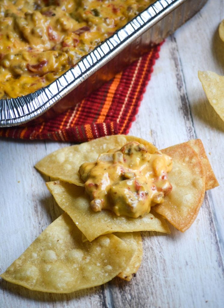 smoked queso dip shown on a stack of freshly fried corn tortilla chips on a wooden table top