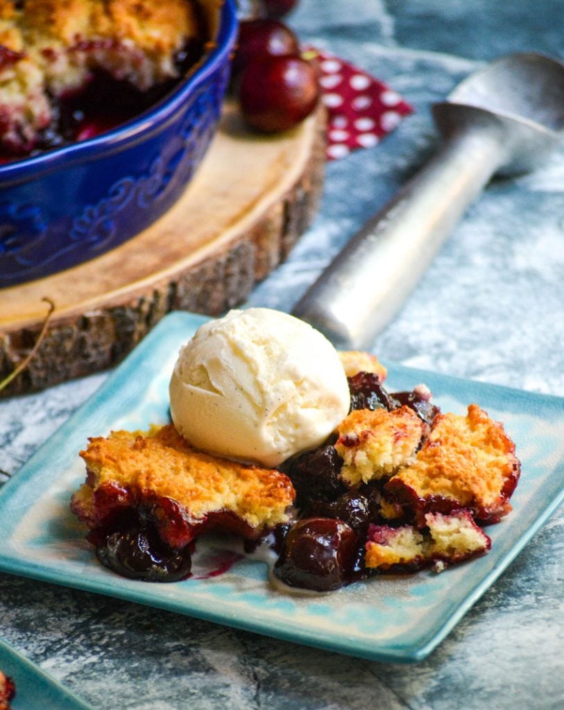 sweet cherry cobbler served on light blue plates with a scoop of vanilla ice cream