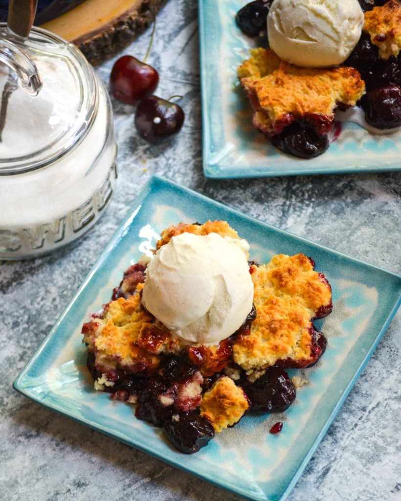 sweet cherry cobbler served on light blue plates with a scoop of vanilla ice cream