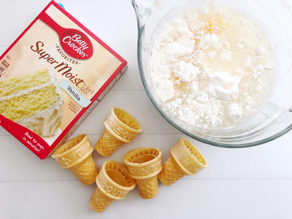 ice cream cone cupcake ingredients in a glass mixing bowl with a box of cake mix & cones shown in the background