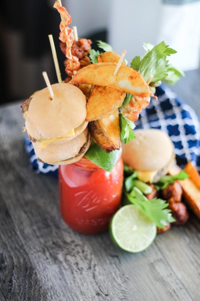 ultimate bloody mary in a Mason jar with a variety of skewered appetizers for garnish